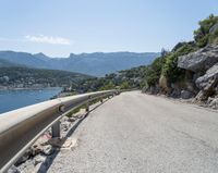 there is a motorcycle that is going up the hill on a curved road, overlooking the water