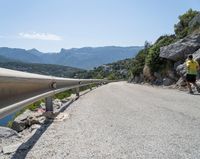 there is a motorcycle that is going up the hill on a curved road, overlooking the water