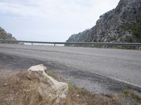 a bike and a car are riding down an empty road with mountains in the background