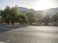 a motorcycle with a rider sits in front of it on a road near trees and other hills