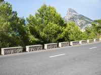 an empty road between two wooded hills and bushes on either side of the road is a steep hill with a steeped top