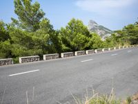 an empty road between two wooded hills and bushes on either side of the road is a steep hill with a steeped top