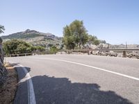 a motorcycle rider riding down the street on a mountain road overlooking a bridge and rocks