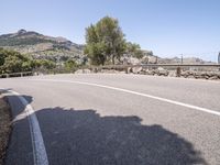 a motorcycle rider riding down the street on a mountain road overlooking a bridge and rocks