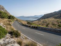 the open road stretches across the mountains past a body of water, which is partially submerged by hills