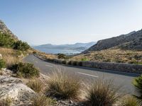 the open road stretches across the mountains past a body of water, which is partially submerged by hills