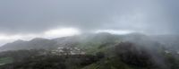 small houses on a hill in the middle of a town below clouds and dark skies