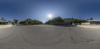 a panoramic image of a very empty street and sun shining down the sky