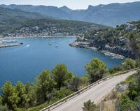 two cyclists riding along the path near a bay and mountains as people ride in the water