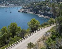 two cyclists riding along the path near a bay and mountains as people ride in the water