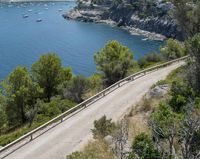 two cyclists riding along the path near a bay and mountains as people ride in the water