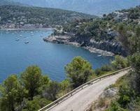 two cyclists riding along the path near a bay and mountains as people ride in the water