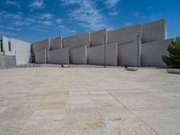 the gray concrete walls of a building have a line of steps on the left side