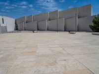 the gray concrete walls of a building have a line of steps on the left side