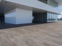 wooden floors in an empty outdoor area, with large windows to the side and a sky view of the city
