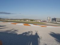 the green road and orange and white stripe line at an event near the racetrack and stadium