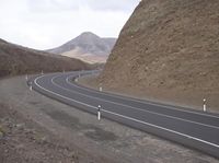 there is an empty roadway that leads to the mountainside as well as a mountain side