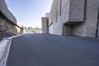 a road in front of some buildings with a sidewalk by it on a bright blue day