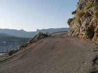 a person on their bike riding down a long cliff side road next to a body of water