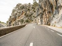 a road in the mountains with a long curve at the bottom of it with a white line painted on the side