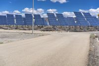 a parking lot with several rows of solar panels and an empty area in the background