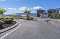 a long winding road passing by a building and palm trees in the center of the city