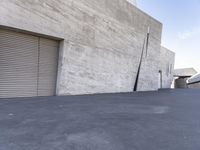 a skateboarder is going down the street in front of an industrial building with shutters