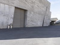 a skateboarder is going down the street in front of an industrial building with shutters