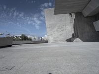 a man on a skateboard riding a concrete walkway and wall that looks like a rock