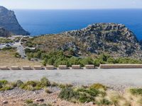 road running on edge of mountain overlooking ocean and large rock outcroppings