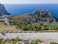 road running on edge of mountain overlooking ocean and large rock outcroppings