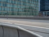 a person riding their skateboard on the side of an empty road on a bridge