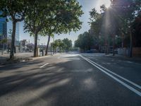 an empty street in front of a building and trees on the other side of the road