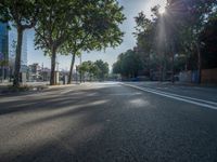 an empty street in front of a building and trees on the other side of the road