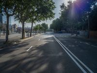 an empty street in front of a building and trees on the other side of the road