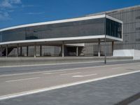 a building made of concrete and glass on the side of the road by the ocean