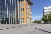 an empty street in front of tall modern buildings on a sunny day in europe, with blue skies above and trees,