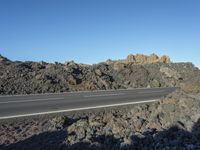 a truck on the road in front of the mountain side rocks and rock formations under it