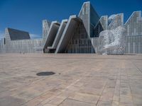 a white building with several steps and large glass panels in the facade is a mosaic that depicts a man