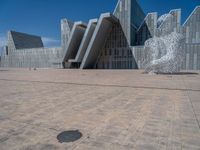 a white building with several steps and large glass panels in the facade is a mosaic that depicts a man