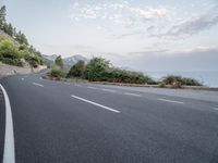 a empty road on a sunny day with white lines going through the center of the road