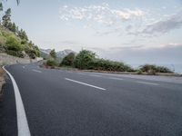 a empty road on a sunny day with white lines going through the center of the road