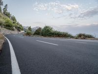 a empty road on a sunny day with white lines going through the center of the road