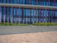 a building with pink glass and purple striped exterior is shown with the brick path on the left