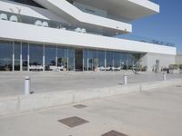 a building that has windows overlooking an outdoor area with benches, chairs, and table on cement