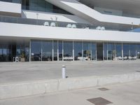 a building that has windows overlooking an outdoor area with benches, chairs, and table on cement