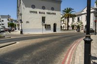 street scene with white building and palm trees on corner next to roadway and red curb