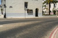 an intersection with a street sign and sign for the theatre, a building with a store on it, near palm trees