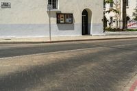 an intersection with a street sign and sign for the theatre, a building with a store on it, near palm trees