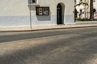 an intersection with a street sign and sign for the theatre, a building with a store on it, near palm trees